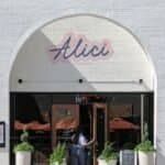 Elegant restaurant exterior in Atlanta featuring entrance with potted plants and signage.