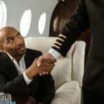 A businessman shakes hands with a pilot inside a luxurious private jet cabin.