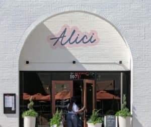 Elegant restaurant exterior in Atlanta featuring entrance with potted plants and signage.