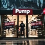 Illuminated shoe store Pump in Brussels with sale signs and reflections at night.