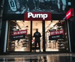 Illuminated shoe store Pump in Brussels with sale signs and reflections at night.