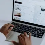 Hands typing on laptop searching Airbnb for accommodation options with map view.