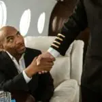 A businessman shakes hands with a pilot inside a luxurious private jet cabin.