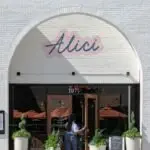 Elegant restaurant exterior in Atlanta featuring entrance with potted plants and signage.
