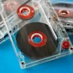 Close-up of vintage transparent audio cassettes with red reels on a bright blue background.