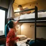 Young couple enjoying a cozy stay in a hostel bunk bed room, perfect for budget travel and bonding.