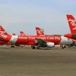 Multiple AirAsia airplanes parked on a tarmac at an airport, showcasing aviation travel.