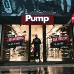Illuminated shoe store Pump in Brussels with sale signs and reflections at night.