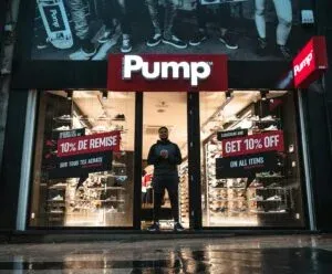 Illuminated shoe store Pump in Brussels with sale signs and reflections at night.