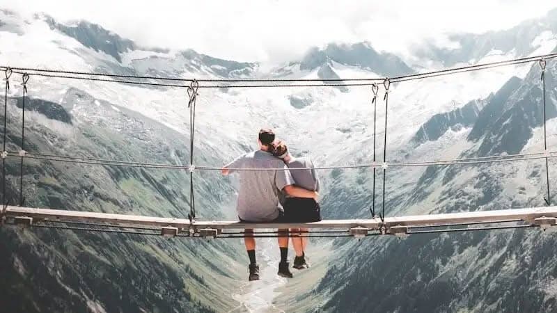 In Cruises Reviews man and woman sitting on hanging bridge at daytime